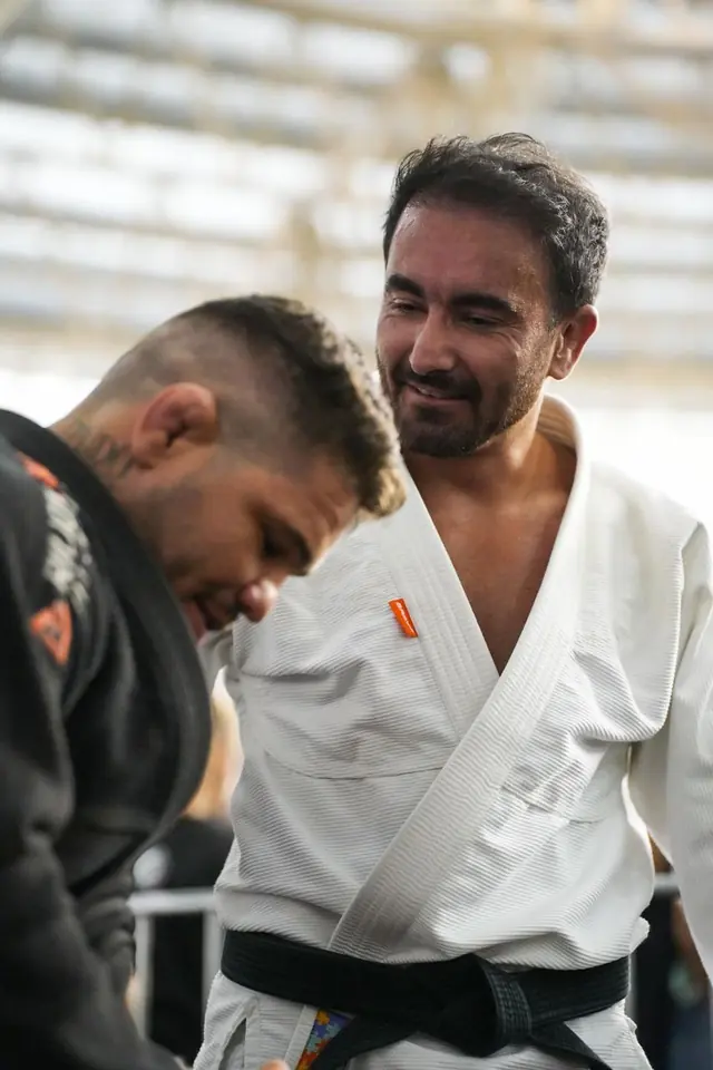 Jaime C. da Luz Jr, faixa preta, sorrindo no tatame com um aluno