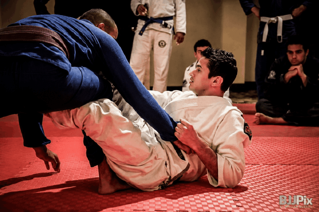 Raspagem no Jiu Jitsu sendo executada com inversão de posição no tatame