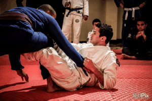 Raspagem no Jiu Jitsu sendo executada com inversão de posição no tatame