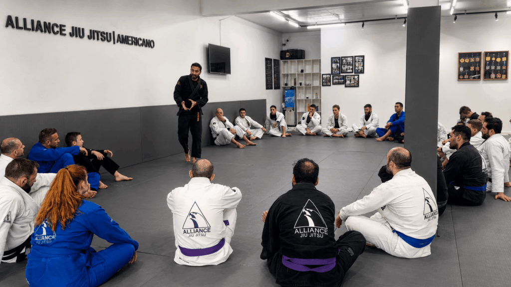 Jaime conduzindo um seminário no centro do tatame com a turma reunida em círculo ao redor